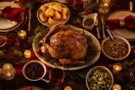 Christmas dinner table set with roast, vegetables and candles